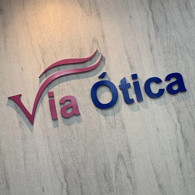 Logotipo da Via Ótica em relevo na parede.